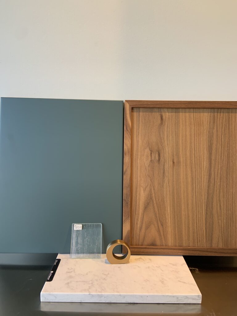 Close-up of English green kitchen cabinets paired with walnut drawer fronts and brass hardware